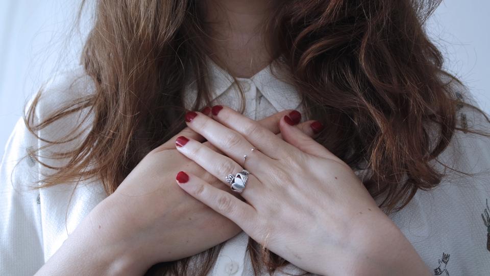 มือไขว้ ทาเล็บสีแดง บนเสื้อเชิ้ตสีขาว